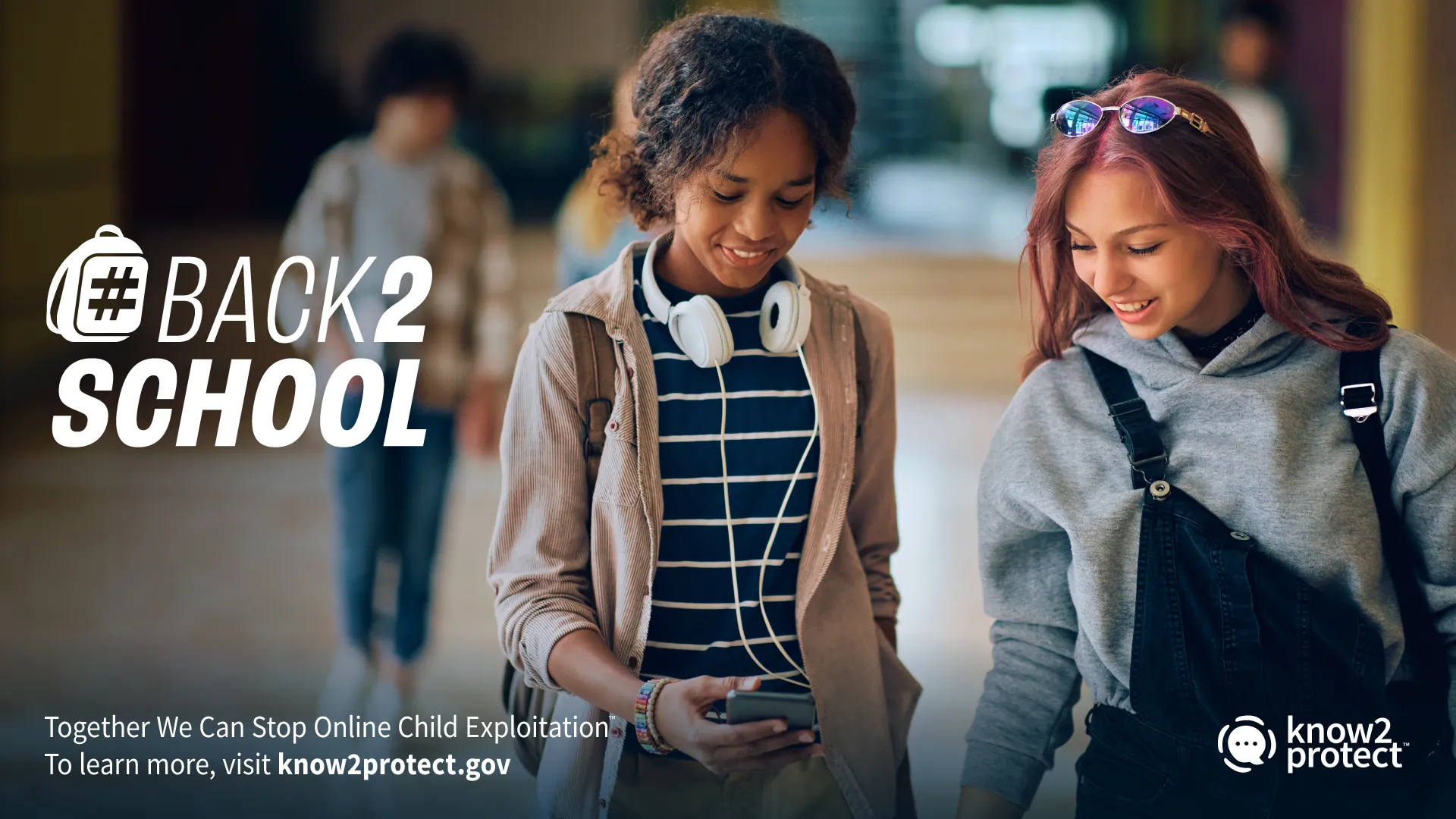 Two students in a school hallway looking at a smartphone. Find online safety tips for kids returning to school from the DHS #Back2School campaign.