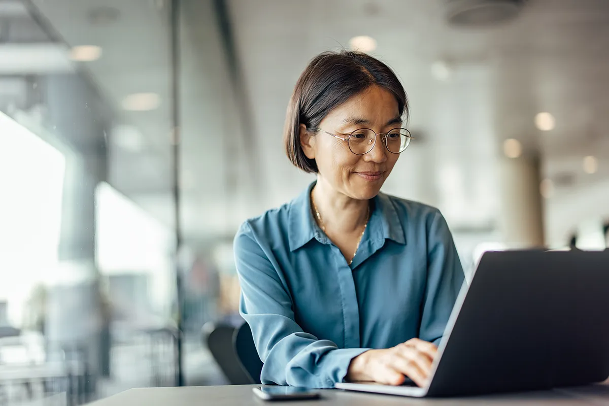 A mandated reporter sits at a table in front of a laptop to renew her online training course. Find out if mandated reporter training expires every year. 