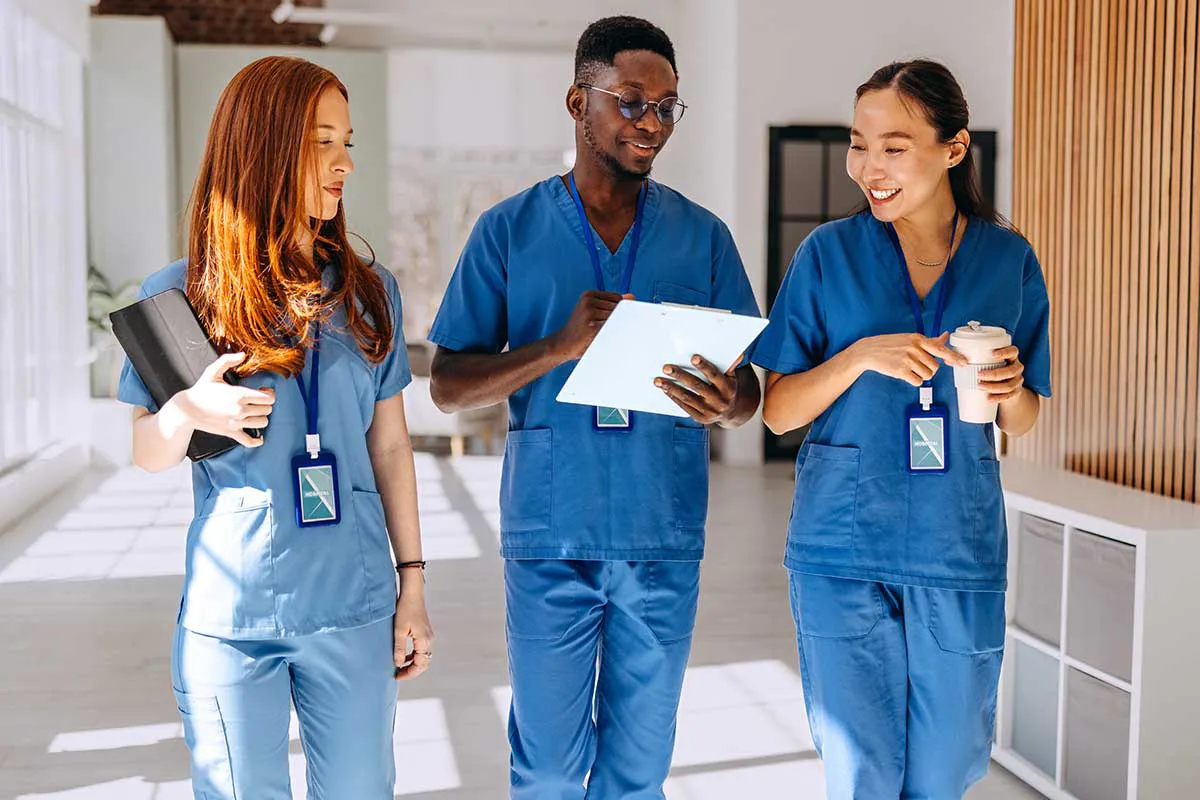 A group of medical professionals walking and reviewing information on a clipboard.